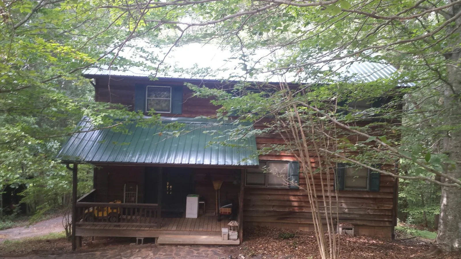 Green metal roof and covered porch on a log cabin in Slate Hill