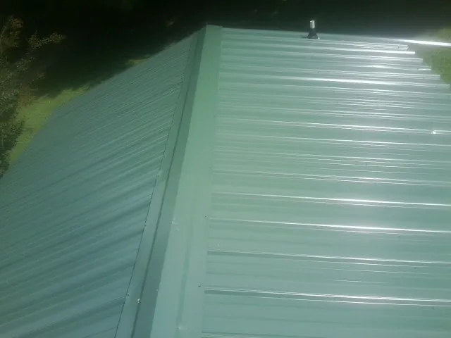 New green metal panels meeting at the ridge of a roof — Flat Roof Repair work by our crew in Slate Hill
