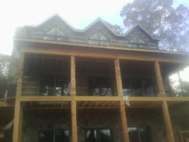 Dormers and porch framing on a large log home under construction — Roof Coating work by our crew in Slate Hill