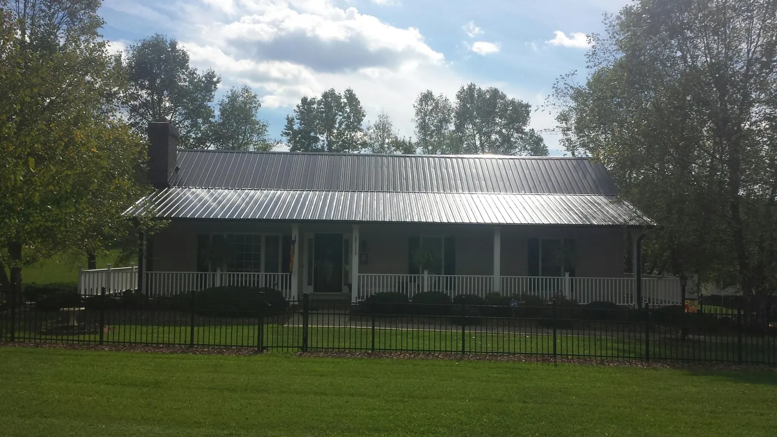 Gray metal roof on a brick ranch with a full width front porch — Gutter Guard Installation work by our crew in Slate Hill