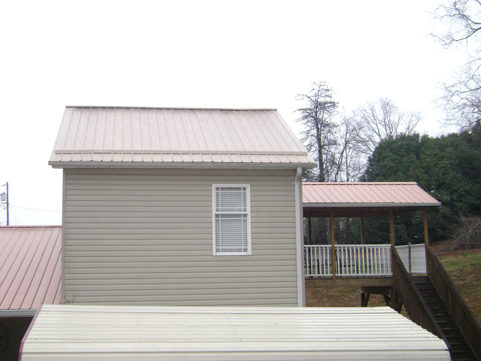Tan metal roofs on a two story addition and attached porch, from a Roof Replacement job in Slate Hill