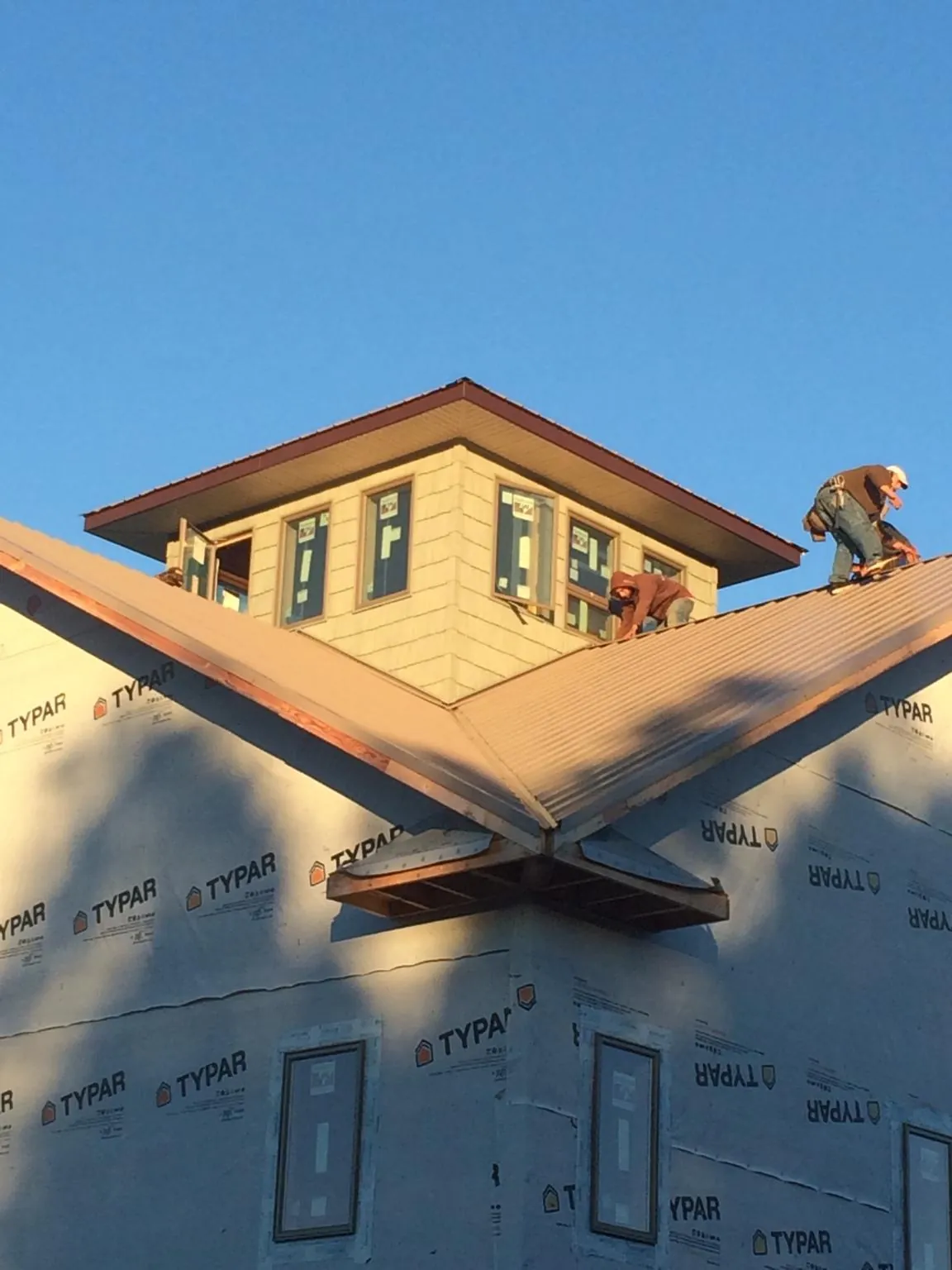 Roofers working around a rooftop cupola on a new metal roof at sunset — Roof Waterproofing in Slate Hill by Roofing Brothers